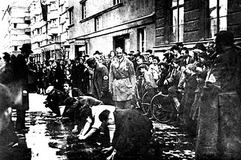 Juden, die im März 1938 in der Hagenmüllergasse gezwungen wurden, die Straße von politischen Parolen zu säubern.