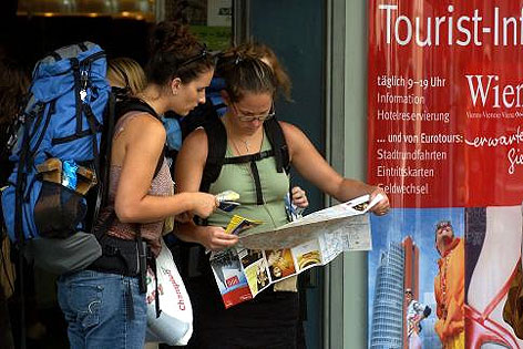 Touristinnen blicken vor Touristinfo auf Stadtplan.