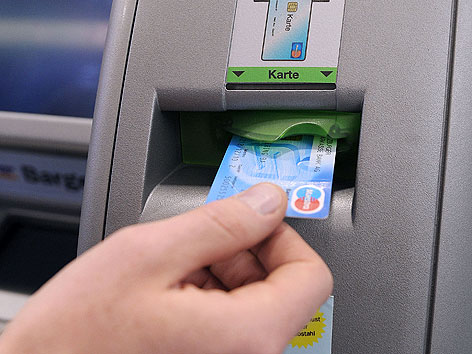Mann steckt Bankomatkarte in  Geldautomaten