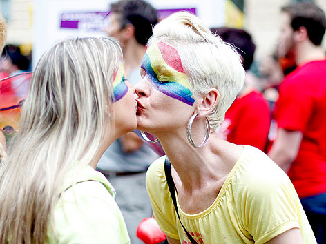 Teilnehmer der Regenbogenparade küssen sich