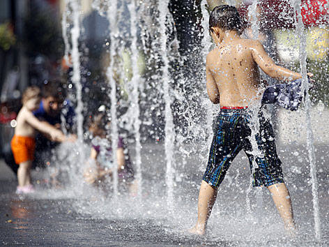 Kinder bei Hitze und hohen Temperaturen bei Wasserfontänen in Wiener Fußgängerzone