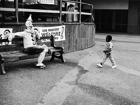 Fotografie von Roger Ballen: Ein kleiner schwarzer Junge läuft auf einen Clown zu