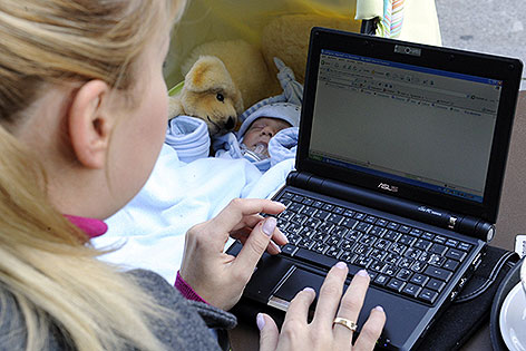 Frau neben Baby am Laptop