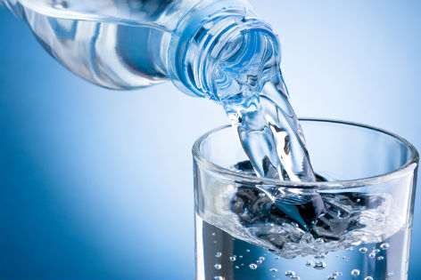 Wasser wird aus Flasche in Glas gefüllt