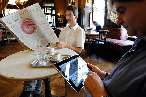 Gäste mit Zeitung und Tablet in Kaffeehaus
