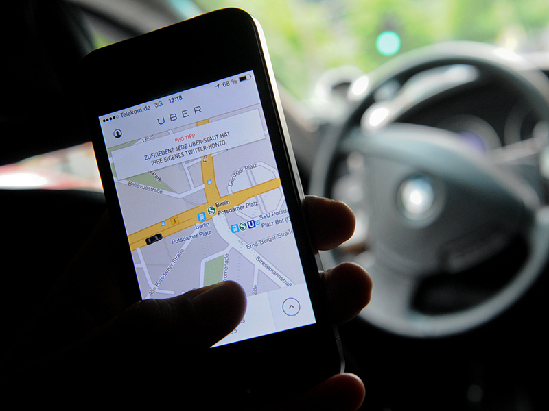 Uber App auf Handy bei Lenkrad