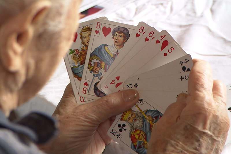 Alter Mann hält Spielkarten